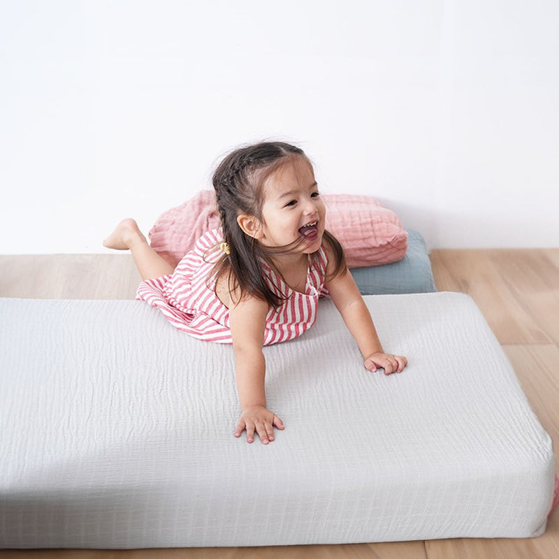 Little girl hopping onto the baby organic mattress by Hush Home 
