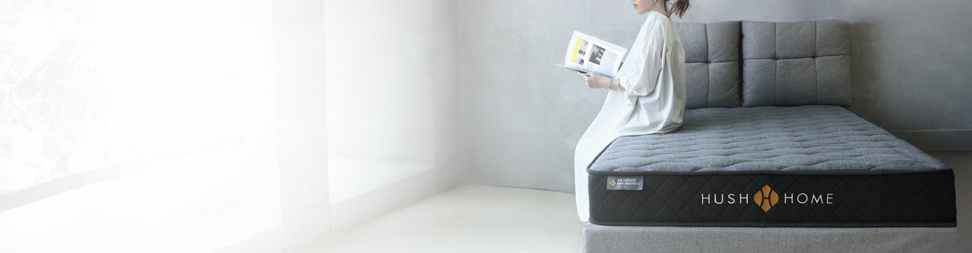 A girl sitting on the Essence Firm Mattress by Hush Home 